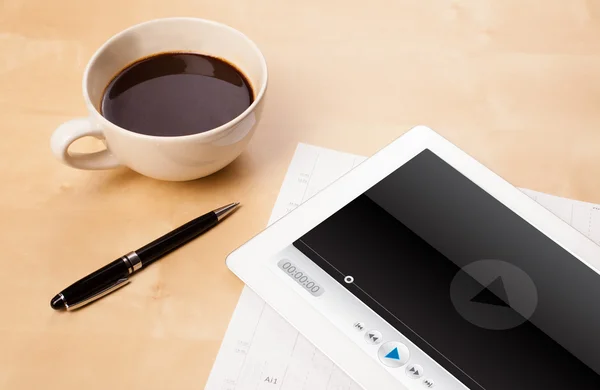 Tablet pc showing media player on screen with a cup of coffee on — Stock Photo, Image