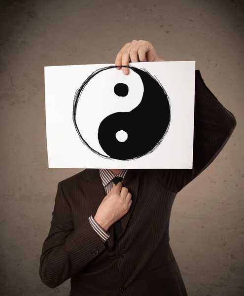 Businessman holding a paper with a yin-yang on it in front of hi — Stock Photo, Image