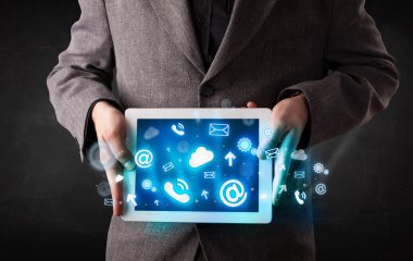 Mavi teknoloji simgeleri ve sembolleri olan bir tablet tutan kişi