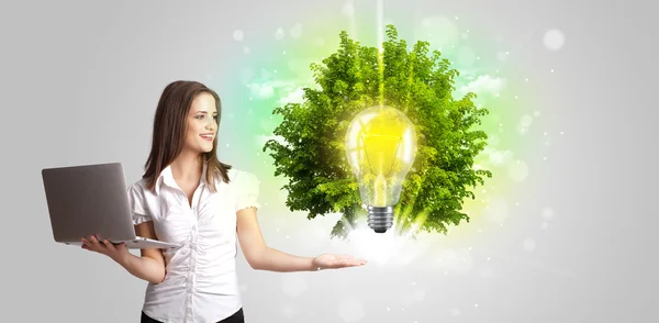 Jong meisje presenteren idee gloeilamp met groene boom — Stockfoto