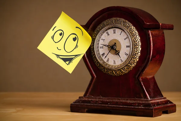 Post-it note with smiley face sticked on a clock — Stock Photo, Image