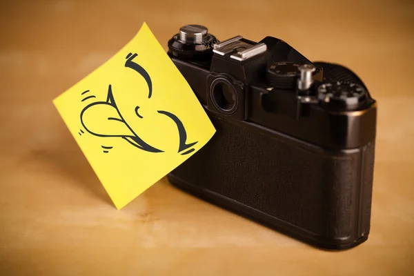 Post-it opmerking met smileygezicht gevezen op fotocamera — Stockfoto