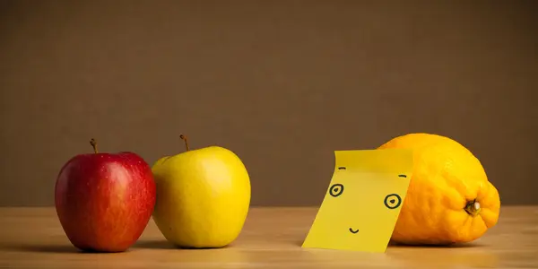 Lemon with post-it note looking at apples — Stock Photo, Image