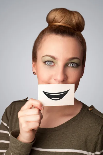 Happy pretty woman holding card with funny smiley — Stock Photo, Image