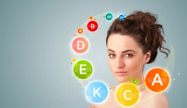 Pretty young girl with colorful vitamin icons and symbols — Stock Photo, Image