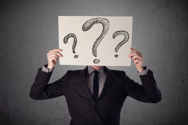 Businessman holding a paper with question marks in front of his — Stock Photo, Image