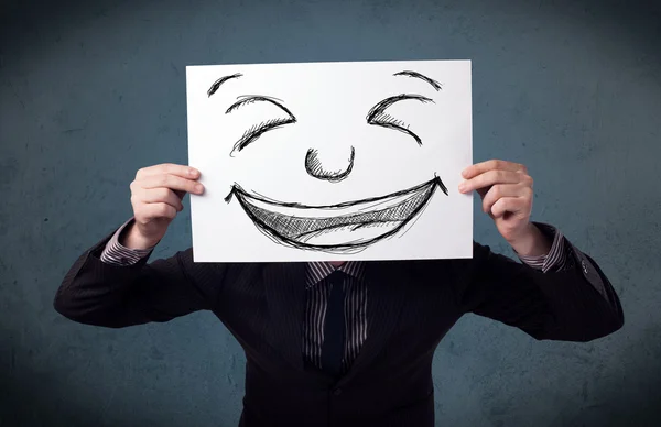 Empresário segurando um papel com rosto sorridente na frente de sua hea — Fotografia de Stock