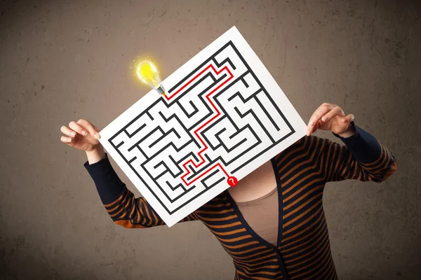 Frau hält ein Papier mit einem Labyrinth davor — Stockfoto
