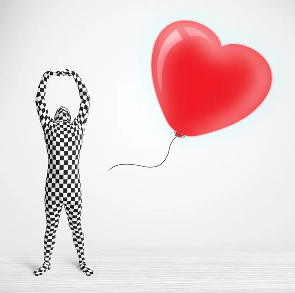 Cute guy in morpsuit body suit looking at a balloon shaped heart — Stock Photo, Image