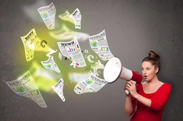 Girl yelling into loudspeaker and newspapers fly out — Stock Photo, Image