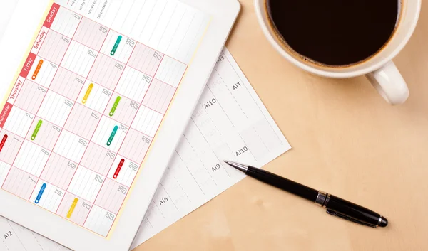 Tablet pc showing calendar on screen with a cup of coffee on a d — Stock Photo, Image