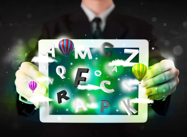 Young person showing tablet with abstract letters and sky — Stock Photo, Image