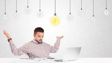 İş adamı masada elinde ampullerle oturuyor.