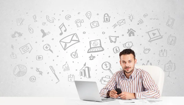 Zakenman zit aan tafel met handgetekende media iconen — Stockfoto