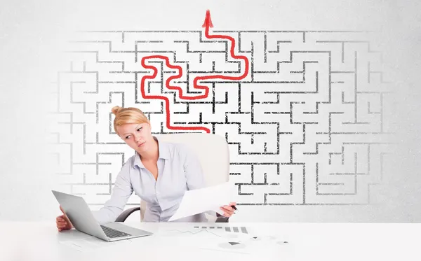 Business woman at desk with labyrinth and arrow — Stock Photo, Image