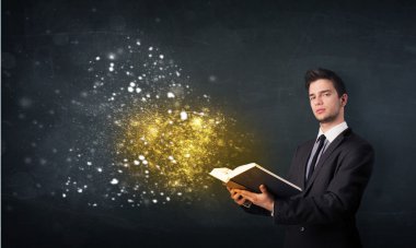 Genç adam sihirli bir kitap okuyor.