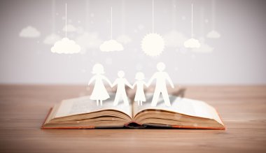 Ailenin karton figürleri açık bir kitabın üzerinde.
