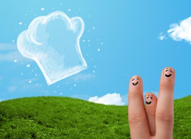 Mutlu gülen yüzlü parmaklar aşçı şapkasının resmine bakıyor.