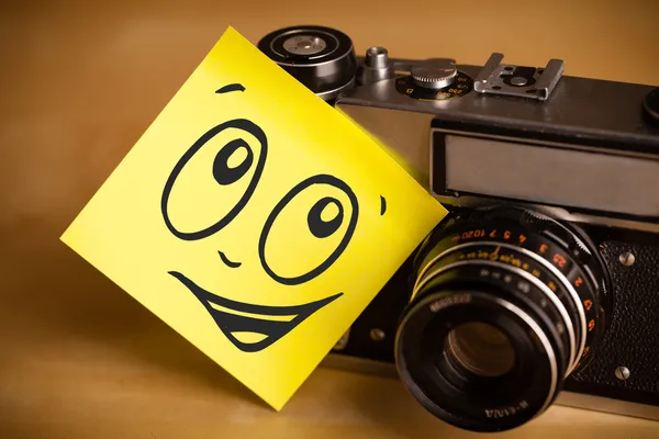 Post-it con faccina sorridente incollata sulla macchina fotografica — Foto Stock