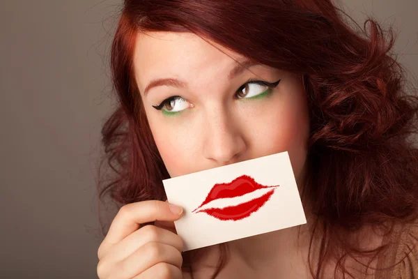 Happy pretty woman holding card with kiss lipstick mark — Stock Photo, Image