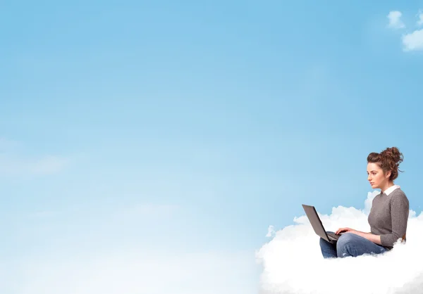 Ung kvinna med laptop sitter på molnet med kopia utrymme — Stockfoto