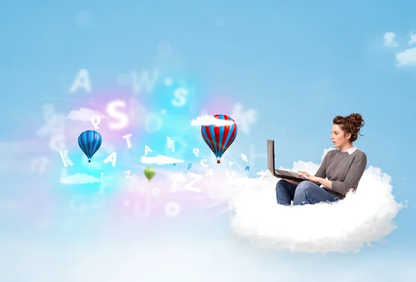 Genç bir kadın dizüstü bilgisayarla bulutlarda oturuyor — Stok fotoğraf
