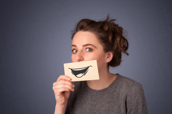 Happy cute girl holding paper with funny smiley drawing — Stock Photo, Image