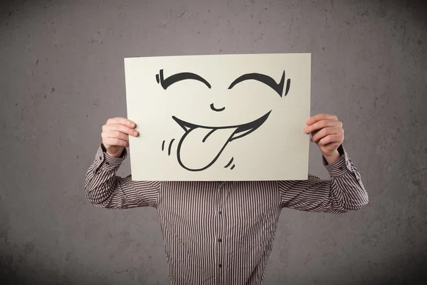 Businessman holding a paper with funny smiley face in front of h — Stock Photo, Image