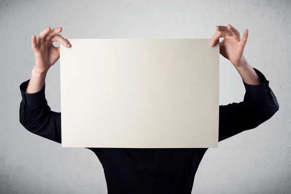 Επιχειρηματίας κρατώντας μπροστά από το κεφάλι του ένα χαρτί με χώρο αντίγραφο — Φωτογραφία Αρχείου