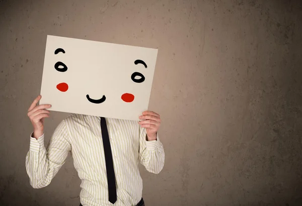 Geschäftsmann hält einen Karton mit einem Smiley darauf — Stockfoto