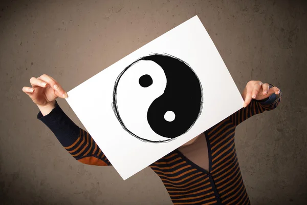Mujer sosteniendo un papel con un yin-yang delante de su cabeza —  Fotos de Stock