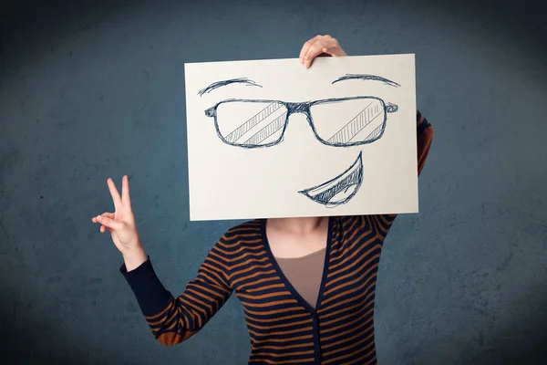 Femme tenant un papier avec le visage souriant devant sa tête — Photo