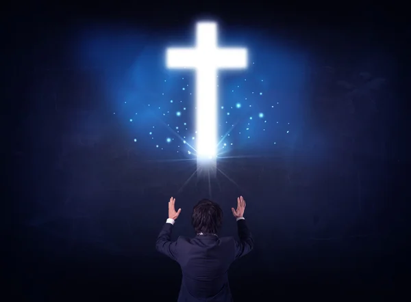 Empresário na frente de uma cruz brilhante — Fotografia de Stock