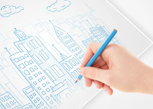 A person drawing sketch of a city with balloons and clouds on a — Stock Photo, Image