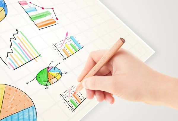 Az üzletember színes grafikonokat és ikonokat rajzol papírra — Stock Fotó