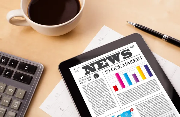 Tablet pc shows news on screen with a cup of coffee on a desk — Stock Photo, Image