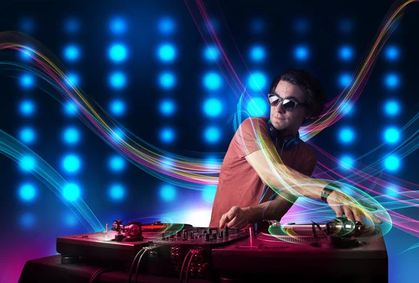 Junger DJ mischt Platten mit bunten Lichtern — Stockfoto