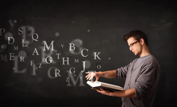 Young man reading a book with alphabet letters — Stock Photo, Image