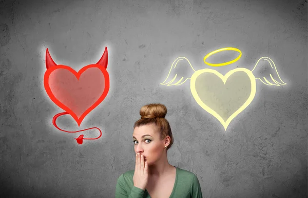 Woman standing between the angel and devil hearts — Stock Photo, Image