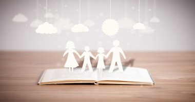 Ailenin karton figürleri açık bir kitabın üzerinde.