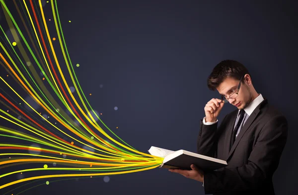 Bonito homem lendo um livro enquanto linhas coloridas estão saindo — Fotografia de Stock