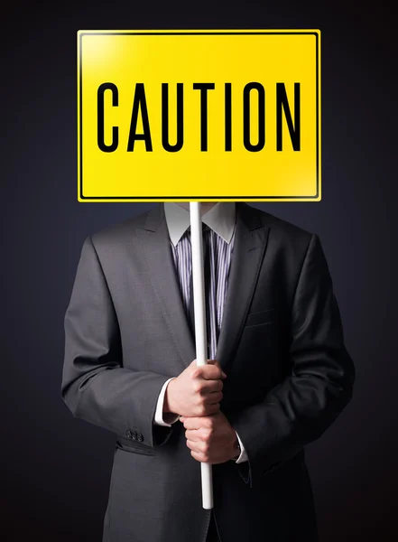 Businessman holding a caution sign — Stock Photo, Image