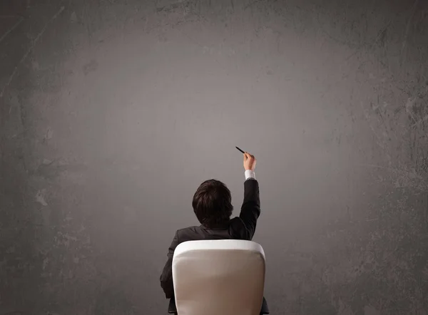 Businessman sitting in front of a wall with copy space — Stock Photo, Image