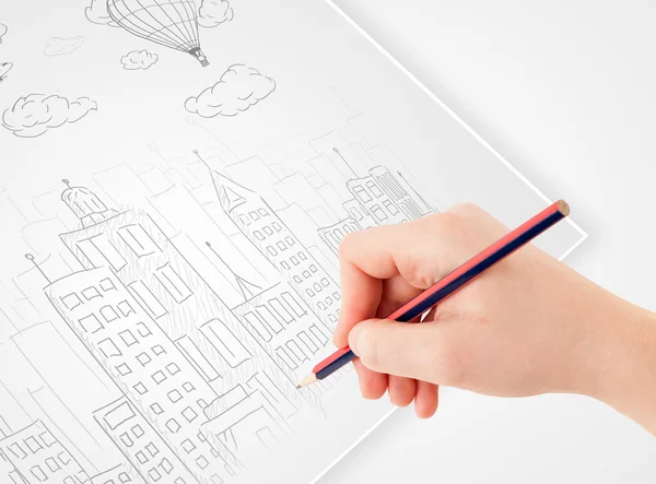 A person drawing sketch of a city with balloons and clouds on a — Stock Photo, Image