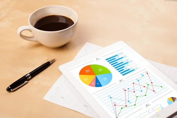 Tablet pc shows charts on screen with a cup of coffee on a desk — Stock Photo, Image