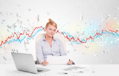 Borsa grafiğiyle masada oturan iş kadını. 