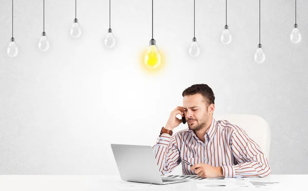 Geschäftsmann sitzt mit Idee Glühbirnen am Tisch — Stockfoto