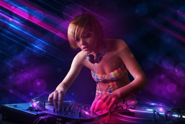 Young DJ playing on turntables with color light effects clipart
