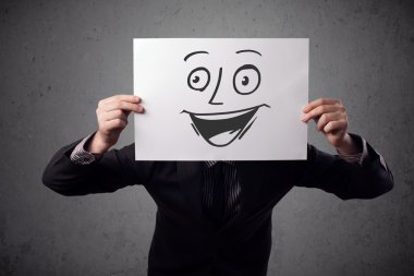 empresario sosteniendo una cartulina con cara sonriente en él en frente 