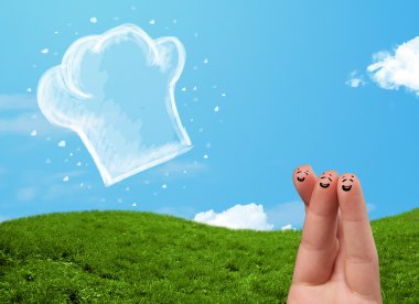 Mutlu gülen yüzlü parmaklar aşçı şapkasının resmine bakıyor.